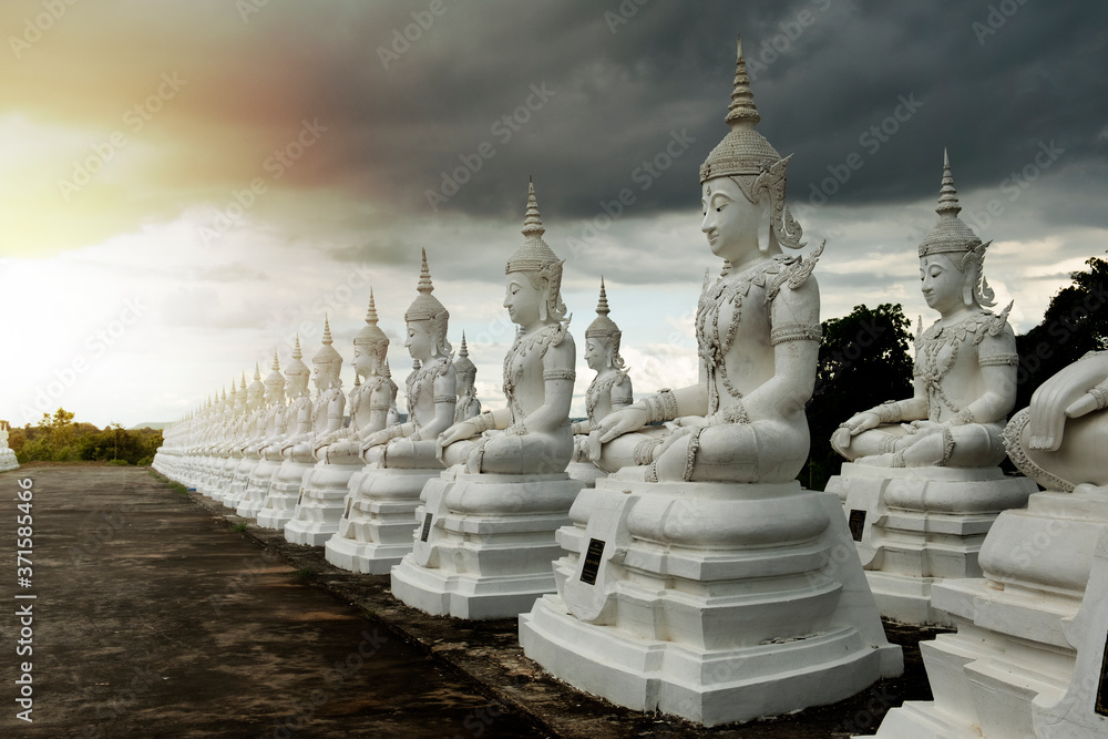row of white buddha statue with dark cloud sky