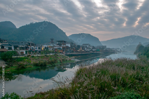 The sunrise scenery of Xibu Street in Zhangjiajie, Hunan province is composed of stilted buildings, ancient buildings, streets, rivers, orange sky and reflection as the background, and quiet effect. C