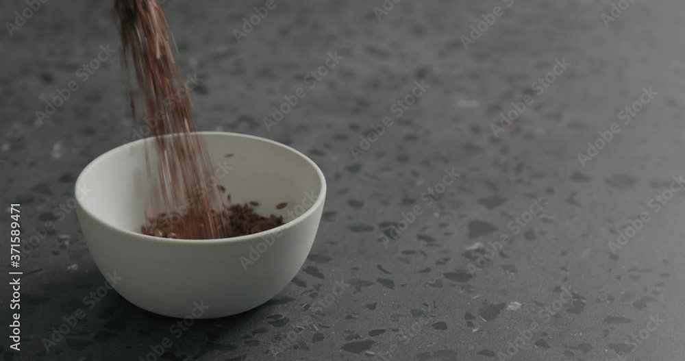 Slow motion flaxseed falling into white bowl on terrazzo countertop Slow motion flaxseed falling into white bowl on terrazzo countertop