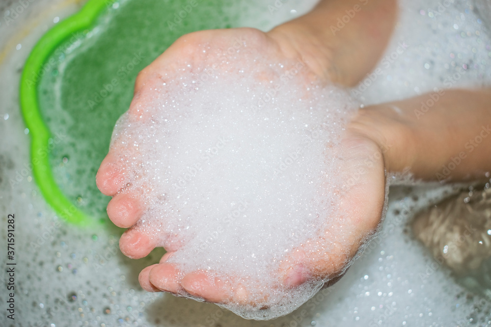 above the water with a bucket in the bathroom in children's hands soap foam above the water with a bucket in the bathroom in children's hands soap foam