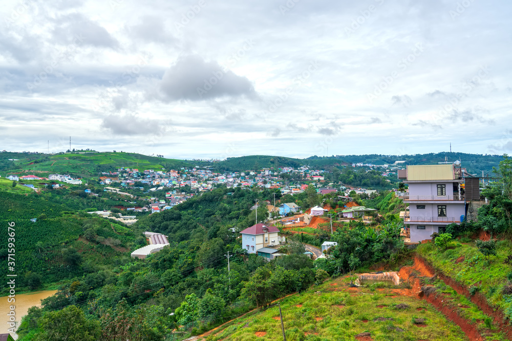 Fototapeta premium Small village in a tea hill valley on a stormy day in the highlands of Da Lat, Vietnam. The place provides a great deal of tea for the whole country