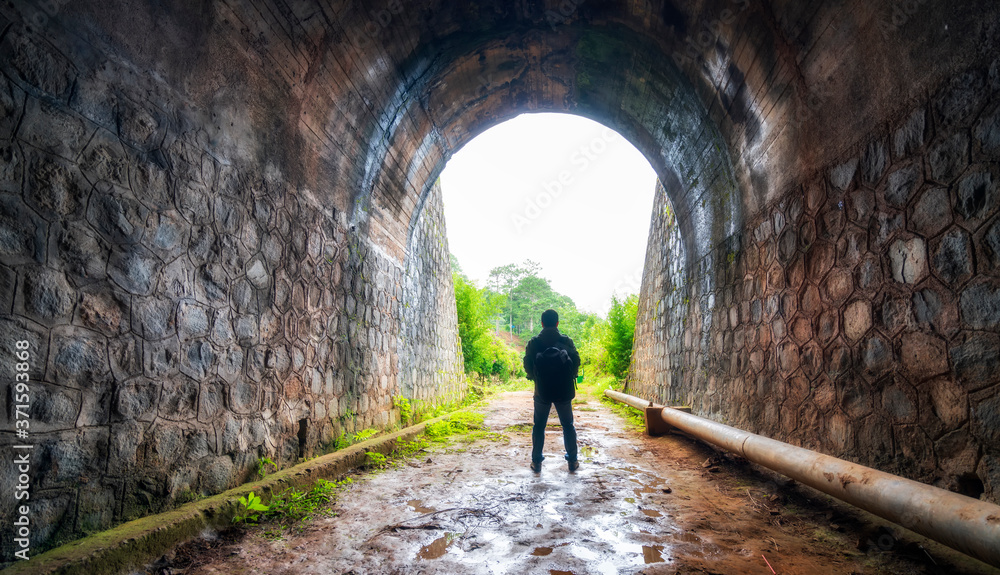 Silhouette traveler man explored in the ancient railway tunnel, abandoned 19th century architecture to today near Da Lat, Vietnam
