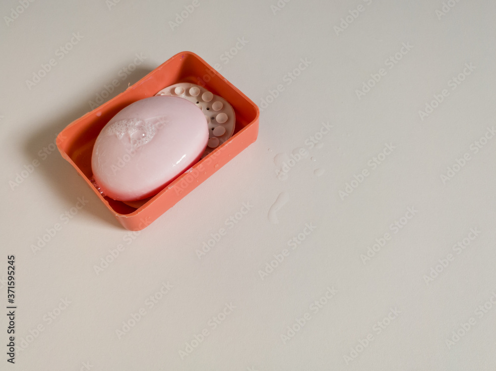 Close-up view of a plastic container with wet soap and foam insulated on a white background in daylight, maintaining cleanliness and hygiene, home and bathroom supplies Close-up view of a plastic container with wet soap and foam insulated on a white background in daylight, maintaining cleanliness and hygiene, home and bathroom supplies
