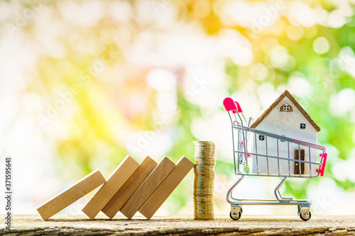 Quadro su tela Collect gold coin for protect hazards from falling wooden block to the home placed in the shopping cart in the public park, Saving money or loan for buy insurance of real estate protection concept