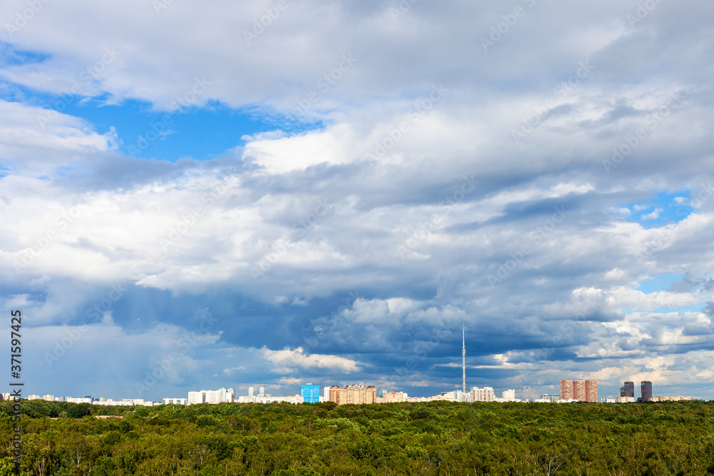 blue cloudy sky over residential districts and green urban park in city on sunny summer day blue cloudy sky over residential districts and green urban park in city on sunny summer day