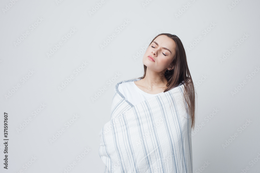 Healthy sleep and drowsiness, beautiful young woman standing wrapped in a blanket