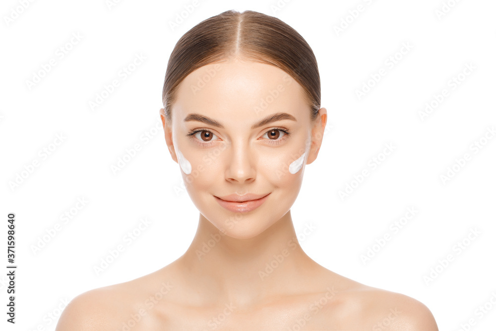 Close-up portrait of young naturally beautiful woman with face cream applied on cheekbones and glowing naked skin, isolated, white background Close-up portrait of young naturally beautiful woman with face cream applied on cheekbones and glowing naked skin, isolated, white background