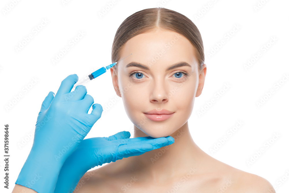 Young blue-eyed female in beauty clinic, ready for filler injection into forehead to keep skin smooth and young, isolated on white background Young blue-eyed female in beauty clinic, ready for filler injection into forehead to keep skin smooth and young, isolated on white background