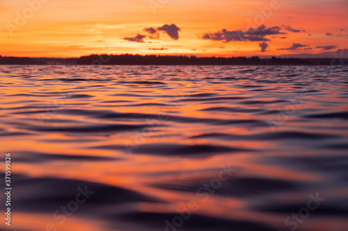 Water surface. View of a Sunset sky background. Dramatic gold sunset sky with evening sky clouds over the sea. View of a Crystal clear sea water texture. Landscape. Small waves. Water reflection