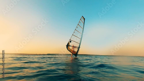 Sailboarder is navigating a windsurf board through the water photo