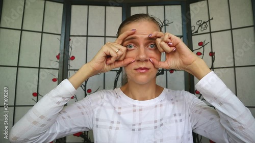Pretty girl makes herself face yoga, anti age, forehead warm-up. Raises her eyebrows, presses down with fingers. Face fitness, modern methods for saving health and beauty. New spa treatment.