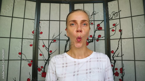 Facial yoga, modeling of new skull shape. Exclusive exercise to develop the muscles of the cheeks and the shape of the nose. Beauty girl stretches her face into an oval and sniffs, wrinkles her nose.