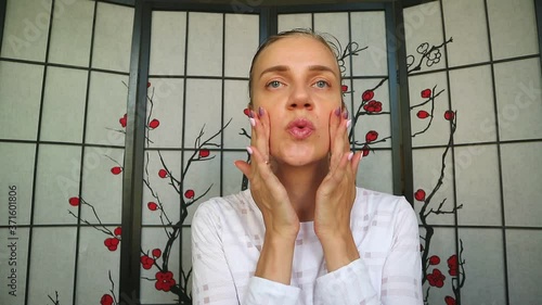 Woman touches her mouth, dreaming about new shape of lips, facial plastic surgery. Pretty beautiful girl smiles and runs her hands over young face, nude makeup. Soft touch, care for beauty and health