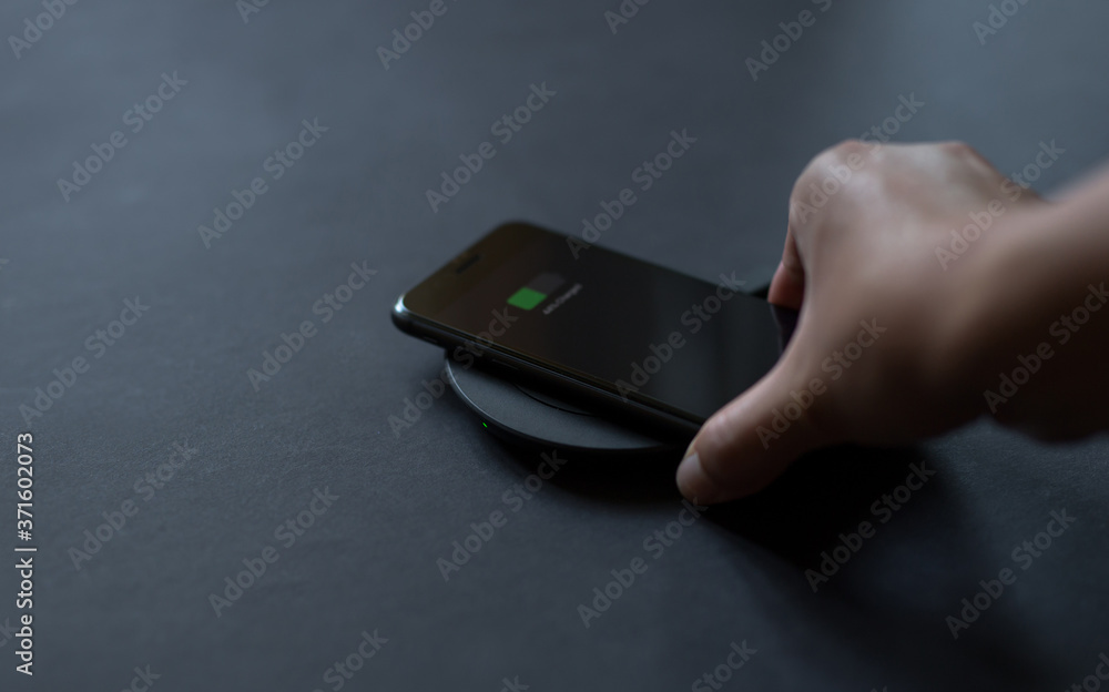 Hand that connects the phone to the wireless charger. Modern technology concept.
Hand that connects the phone to the wireless charger. Modern technology concept.