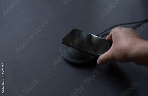 Hand that connects the phone to the wireless charger. Modern technology concept.