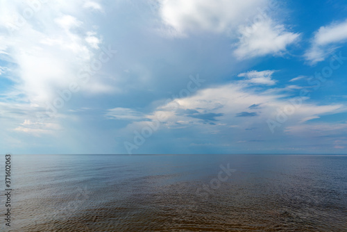 White clouds in the blue sky over the lake. Atmospheric natural background.