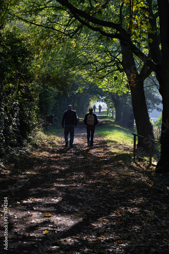 Ramblers Enjoying a Walk Along a Path Covered with Fallen Leaves on a Sunny Autumn Morning Near Ripon Canal, North Yorkshire, England, UK. © SteveGillPhotography