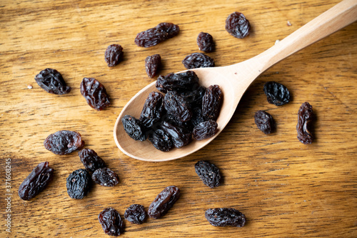 dried raisins on wooden spoon. Selective focus on some raisins.