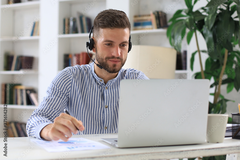 Thoughtful young business man writing something down while working in modern office. Thoughtful young business man writing something down while working in modern office.