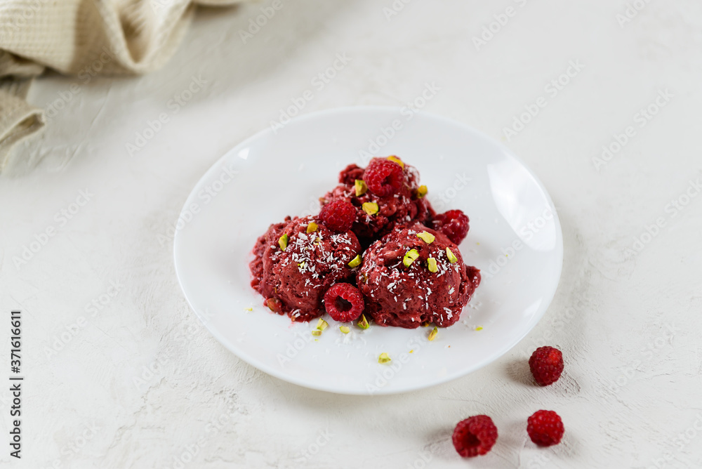 Homemade raspberry ice cream from aquafaba with pistachios and coconut on a white plate. Homemade raspberry ice cream from aquafaba with pistachios and coconut on a white plate.