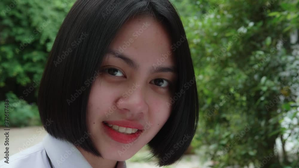 Slow motion of beautiful smiling Asian teen high school girl in white uniform relaxing in the park. Slow motion of beautiful smiling Asian teen high school girl in white uniform relaxing in the park.