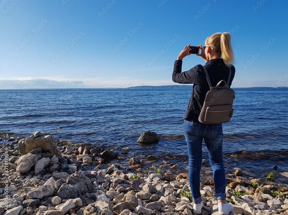 A tourist girl or a traveler with a backpack makes a photo or talks on an online chat or tells subscribers about something.