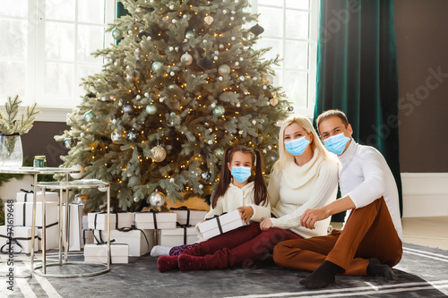 family in protective masks quarantined. Normal life with coronavirus. Lifestyle COVID-19. Quarantine virus protection. christmas