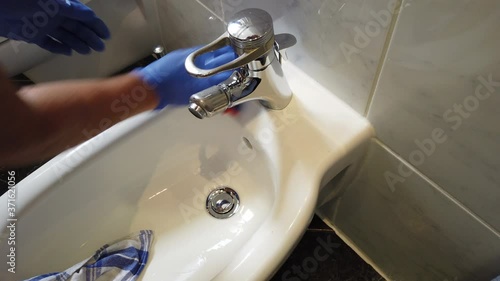 Hand mit Gummihandschuhen reinigt Bad Waschbecken Toilette WC