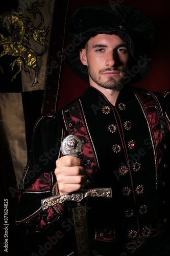 Portrait of handsome king with beard dressed in costume, holding sword and looking at camera photo