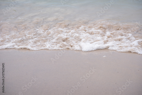Soft ocean wave on tropical sandy beach in rainy season