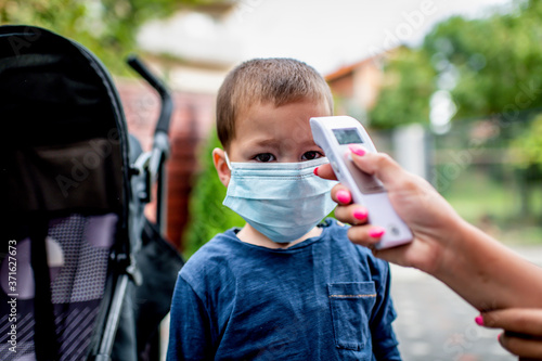 Fotografie A mom checks her son's temperature with a temporal thermometer