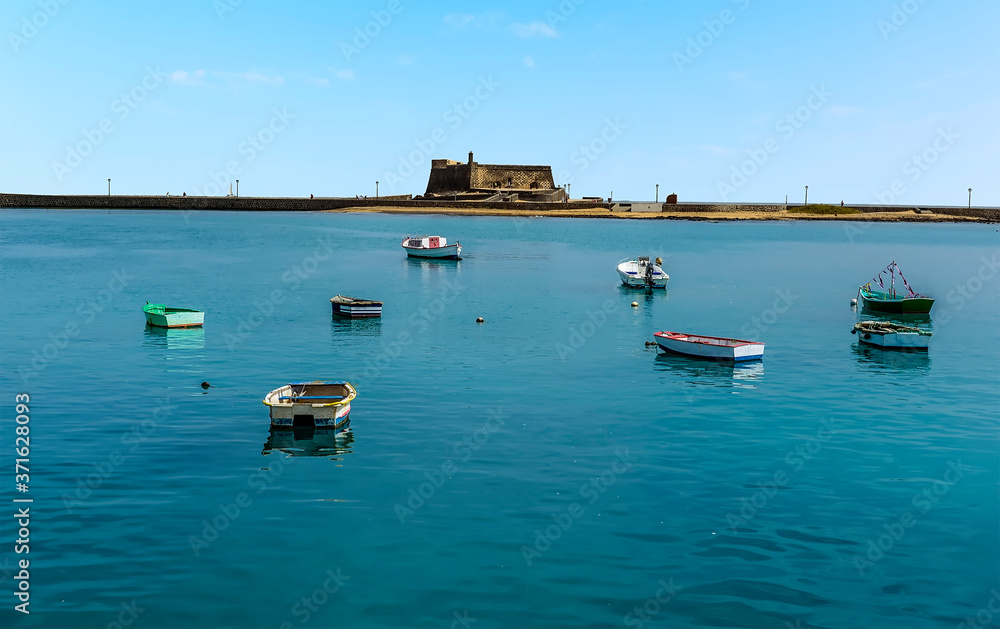 A view across the tranquil waters of the lagoon towards the Castle of Saint Gabriel in Arrecife, Lanzarote on a sunny afternoon