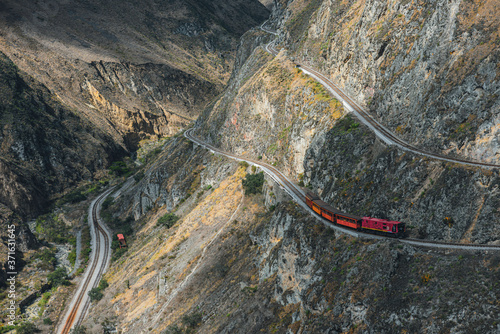 Red train going through the mountain landscape of Chimborazo province, Ecuador