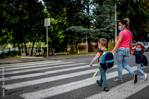 Mother and children going to preschool during corona virus. Surgical mask for illness prevention.