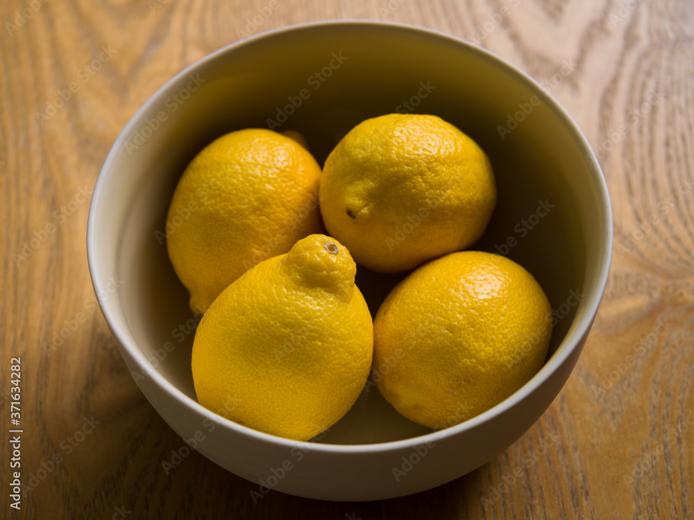 A ceramic bowl with 4 organic yellow lemons. Citrus fruit with vitamin C. A ceramic bowl with 4 organic yellow lemons. Citrus fruit with vitamin C.