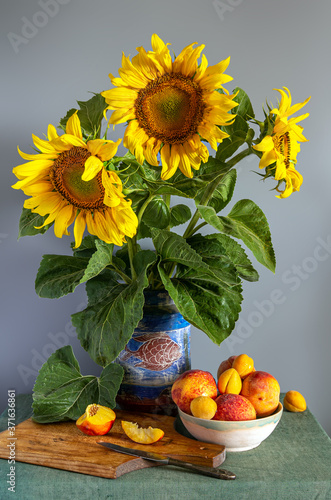 Still life with a bouquet of beautiful sunflowers and ripe fruits. Vintage.