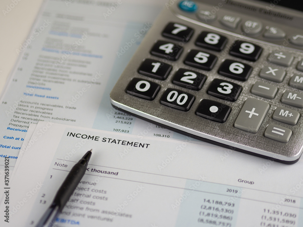 Financial statement concept:Income statement paper sheet with calculator and pen. Financial statement concept:Income statement paper sheet with calculator and pen.