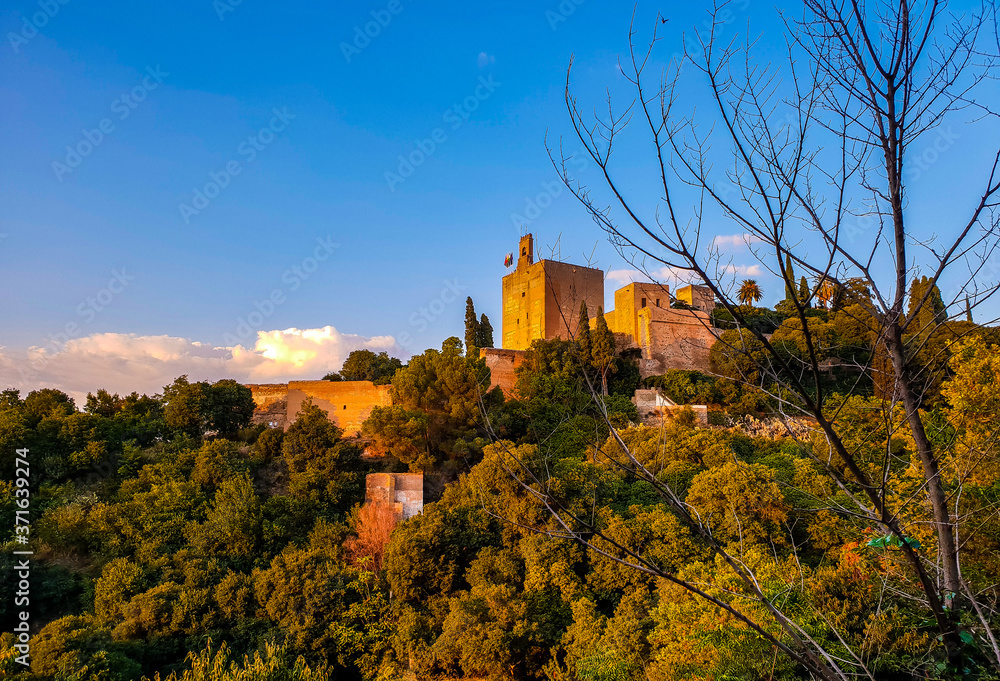 Atardecer de la Alhambra desde una colina de Granada. torre de la vela al fondo con un bosque alrededor