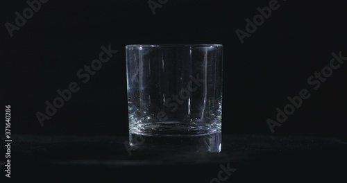 In front of a black background, whiskey is poured into a glass