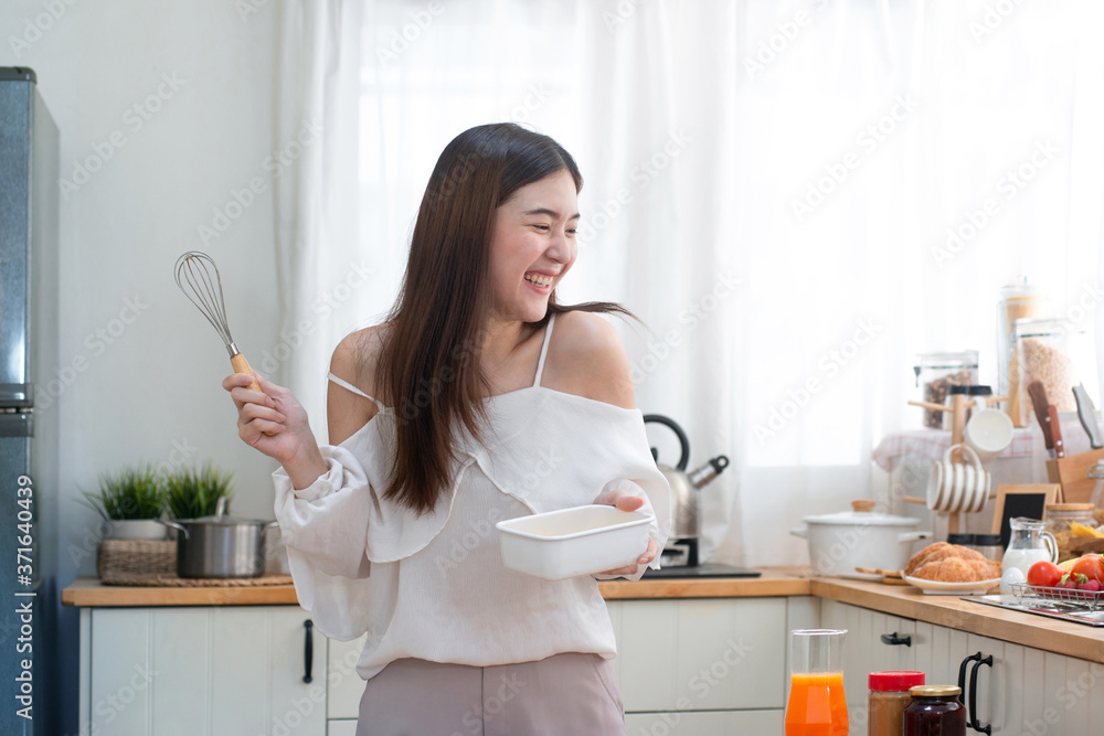 Young Asian woman prepare for making omelet in kitchen, beating eggs to omelet for breakfast, using digital tablet computer Young Asian woman prepare for making omelet in kitchen, beating eggs to omelet for breakfast, using digital tablet computer
