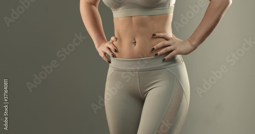 Sports, body shape and fitness concept. Close-up of female abs and bottom. Sportswoman in leggings turning sideways, showing buttocks gluteus and thighs workout progress after gym photo