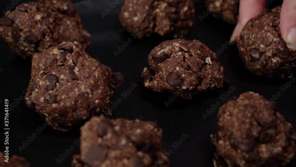 Placing chocolate oatmeal cookie dough ball on pan, Closeup Pan Right Placing chocolate oatmeal cookie dough ball on pan, Closeup Pan Right