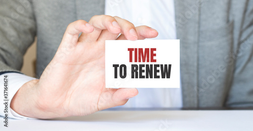 Businessman holding a card with text TIME TO RENEW