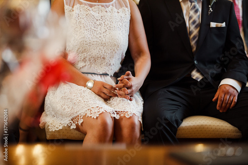 Ein junges Ehepaar sitzt aufgeregt auf dem Standesamt