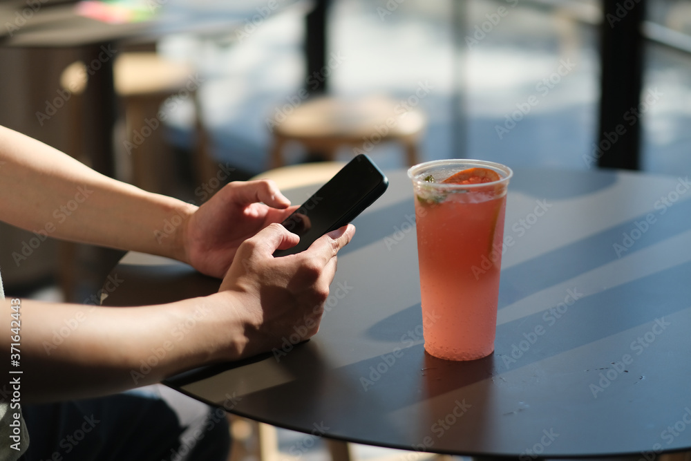 man's hand using smart phone in cafe, with a cup of cold drink on table man's hand using smart phone in cafe, with a cup of cold drink on table