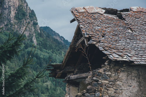 Tejado roto abandonado de casa de montaña con bosque de fondo