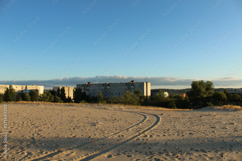 the tracks of a car a car on the light yellow sand in the rays of the setting sun