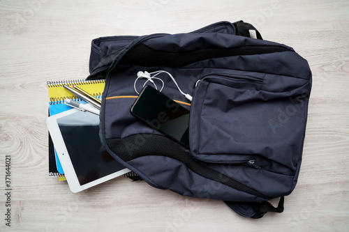 Backpack with notebooks, tablet, phone, headphones and pens.