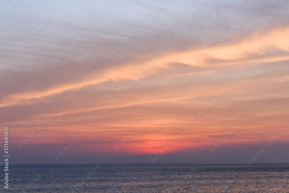 Brilliant orange-red clouds reflected into the ocean in a beautiful sunset