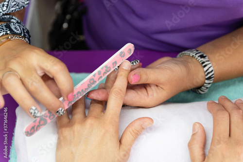 Beautician s hands filing a client s nails
